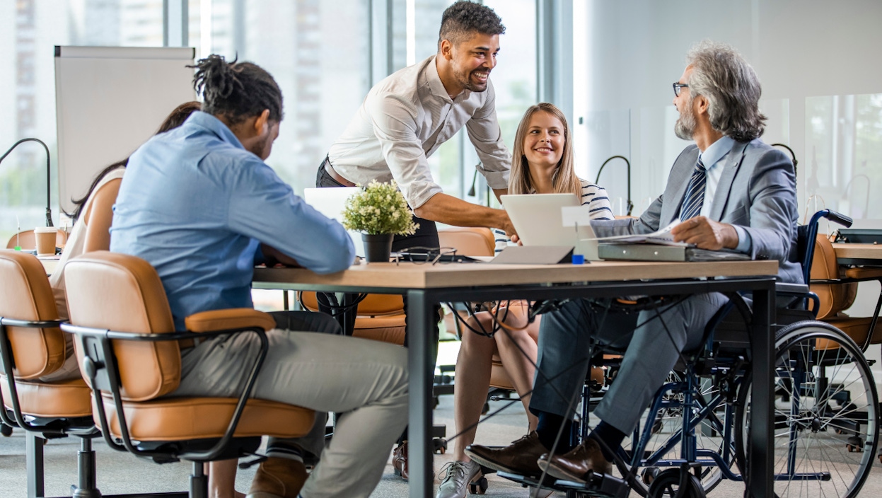 Office shot of five colleagues discussing work demands